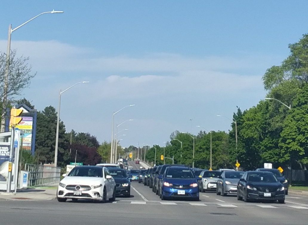 A large group of cars not moving betweeen Leslie Street and 
        the bridge over Highway 404 in the distance